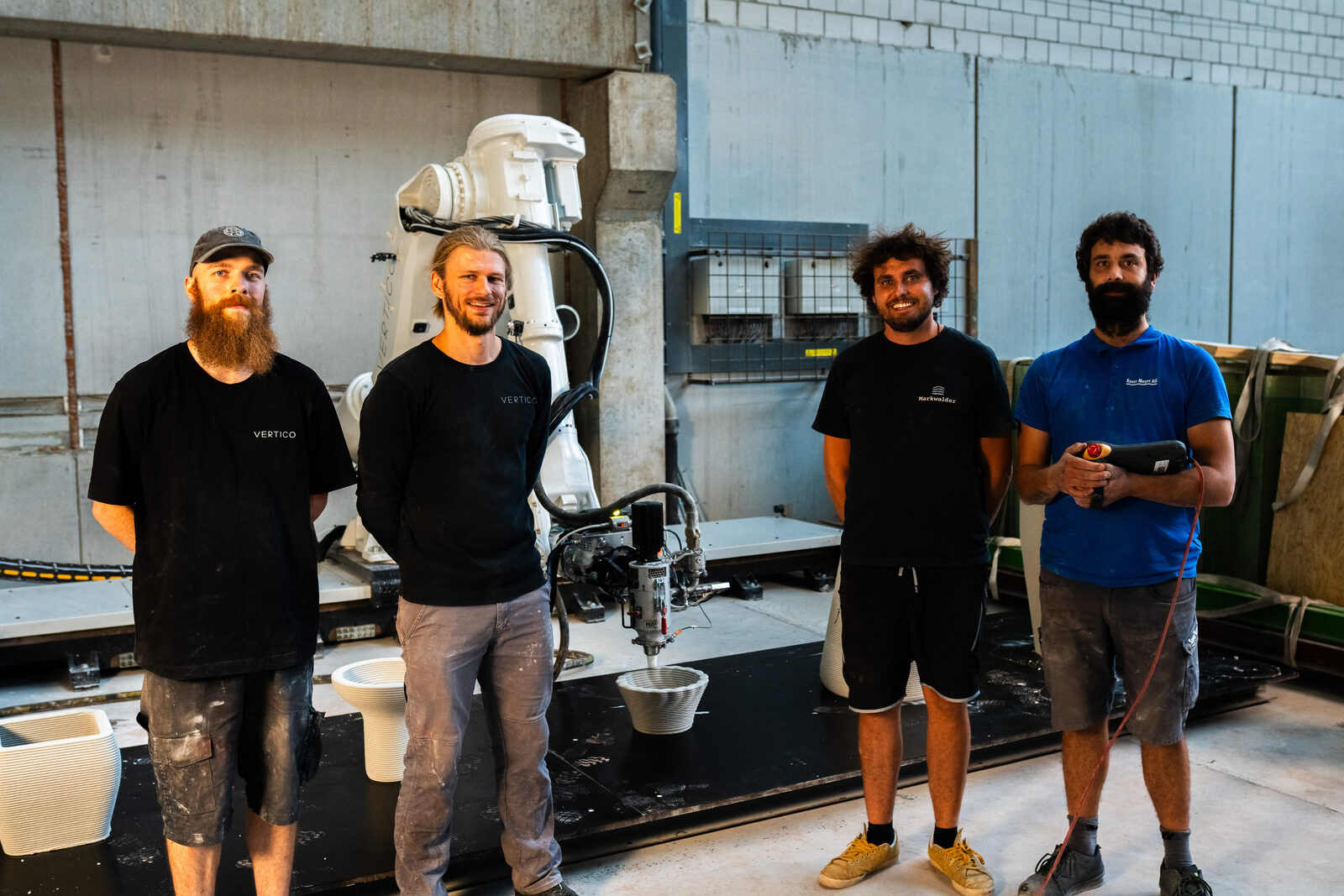 Vier Personen vor dem Roboter, der gerade ein Gefäss druckt