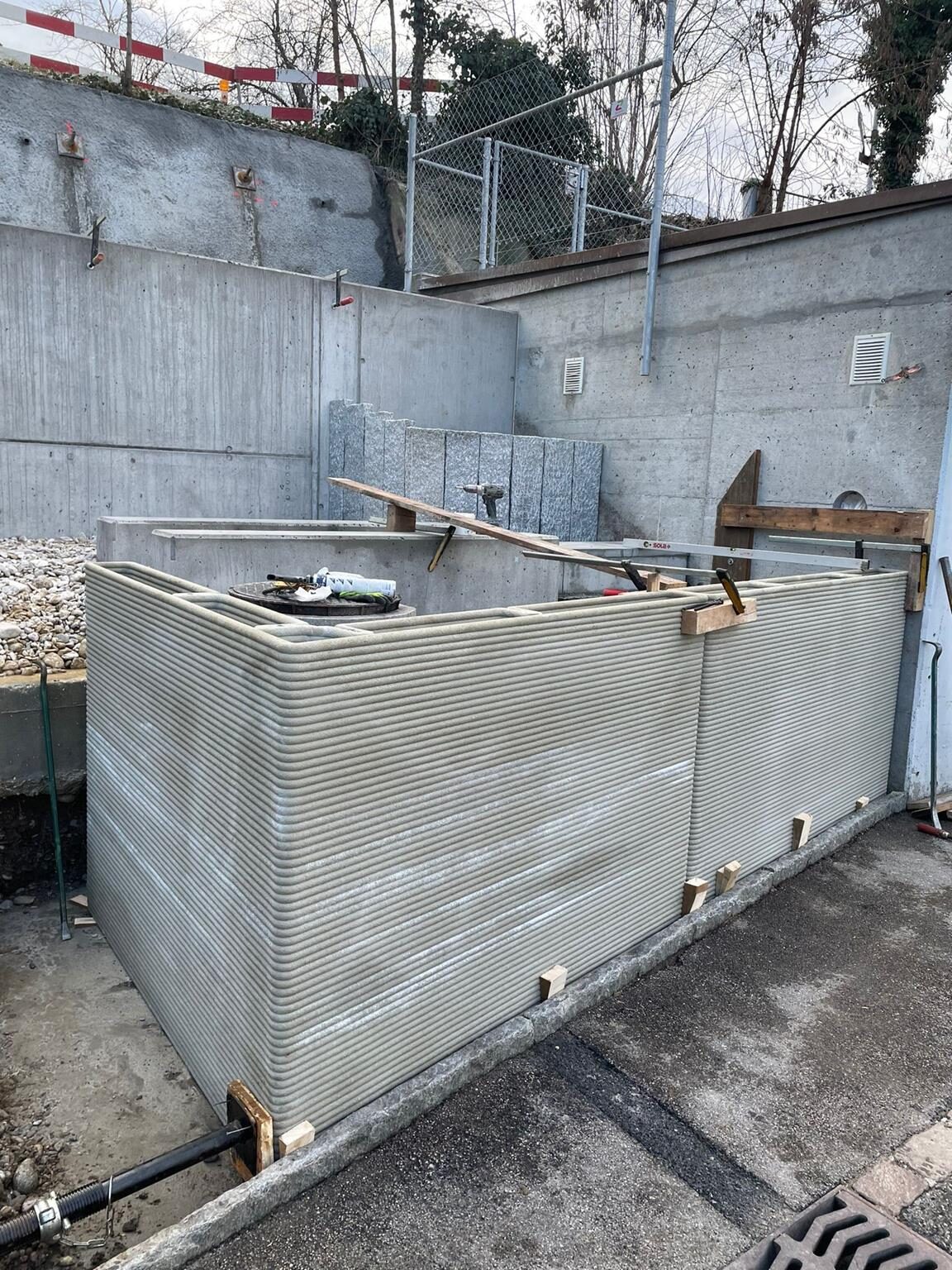 Gedruckte Wandelemente auf einer Baustelle vor einer Betonmauer